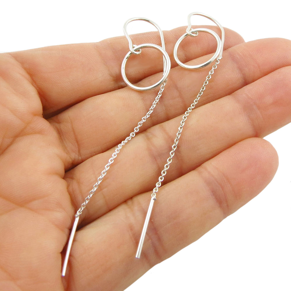 Women's long 925 sterling silver circlle hoop threader earrings on a hand with a white background