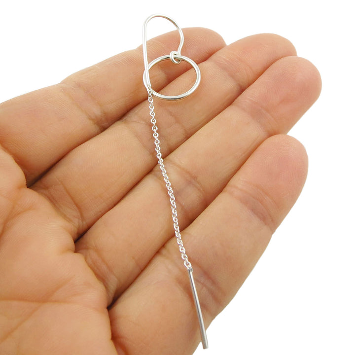 Sterling 925 silver lognm threader chain and circle earring held between fingers on a white background
