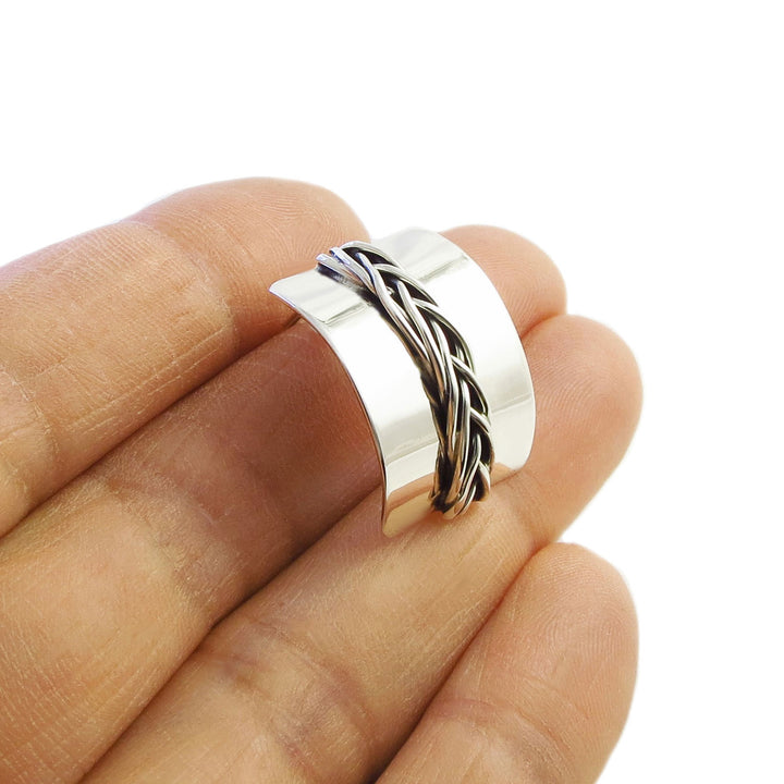 A ingle curved 925 sterling silver earring with braided design on a finger against a white background