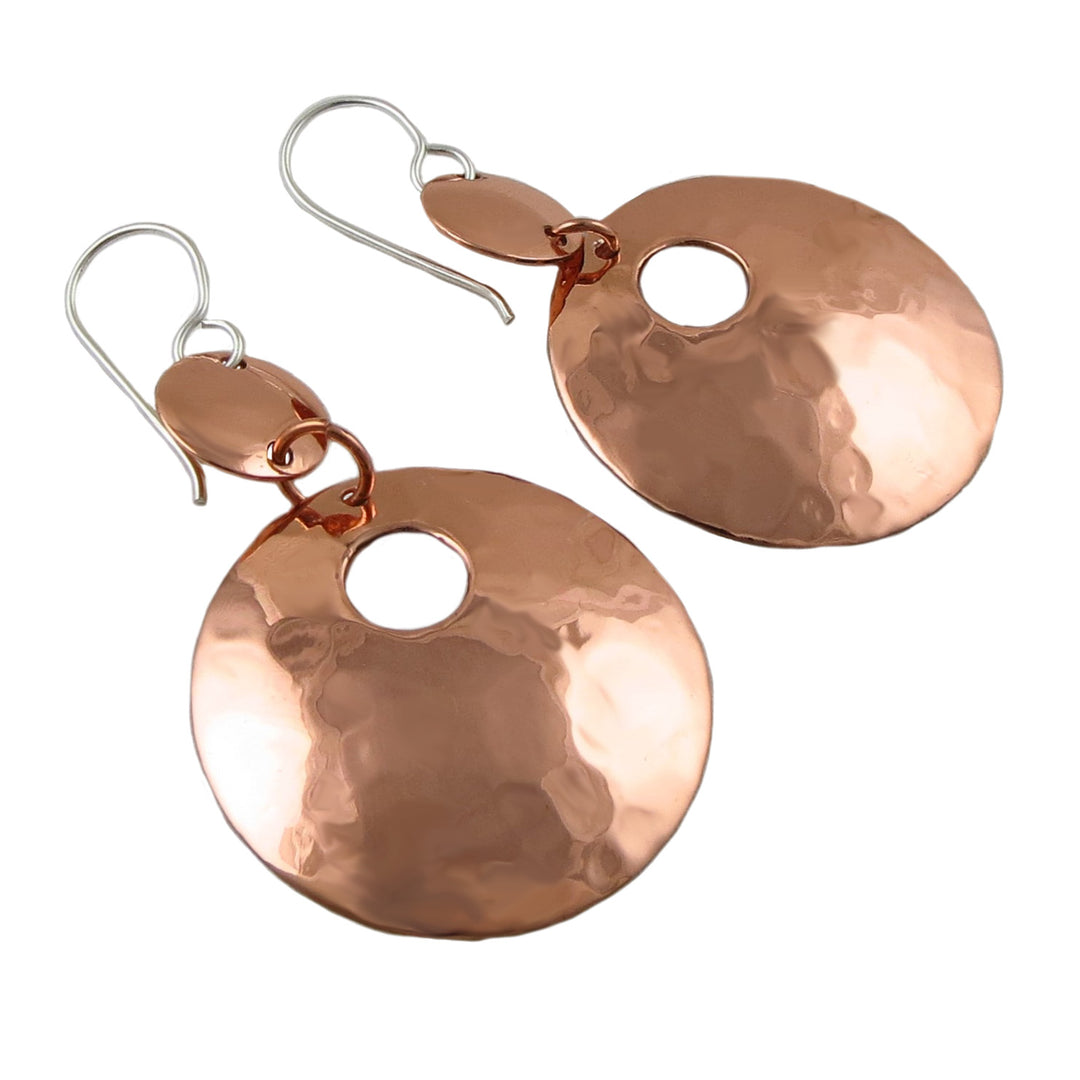 Pair of mixed metal 925 silver and hammered copper earrings on a white background