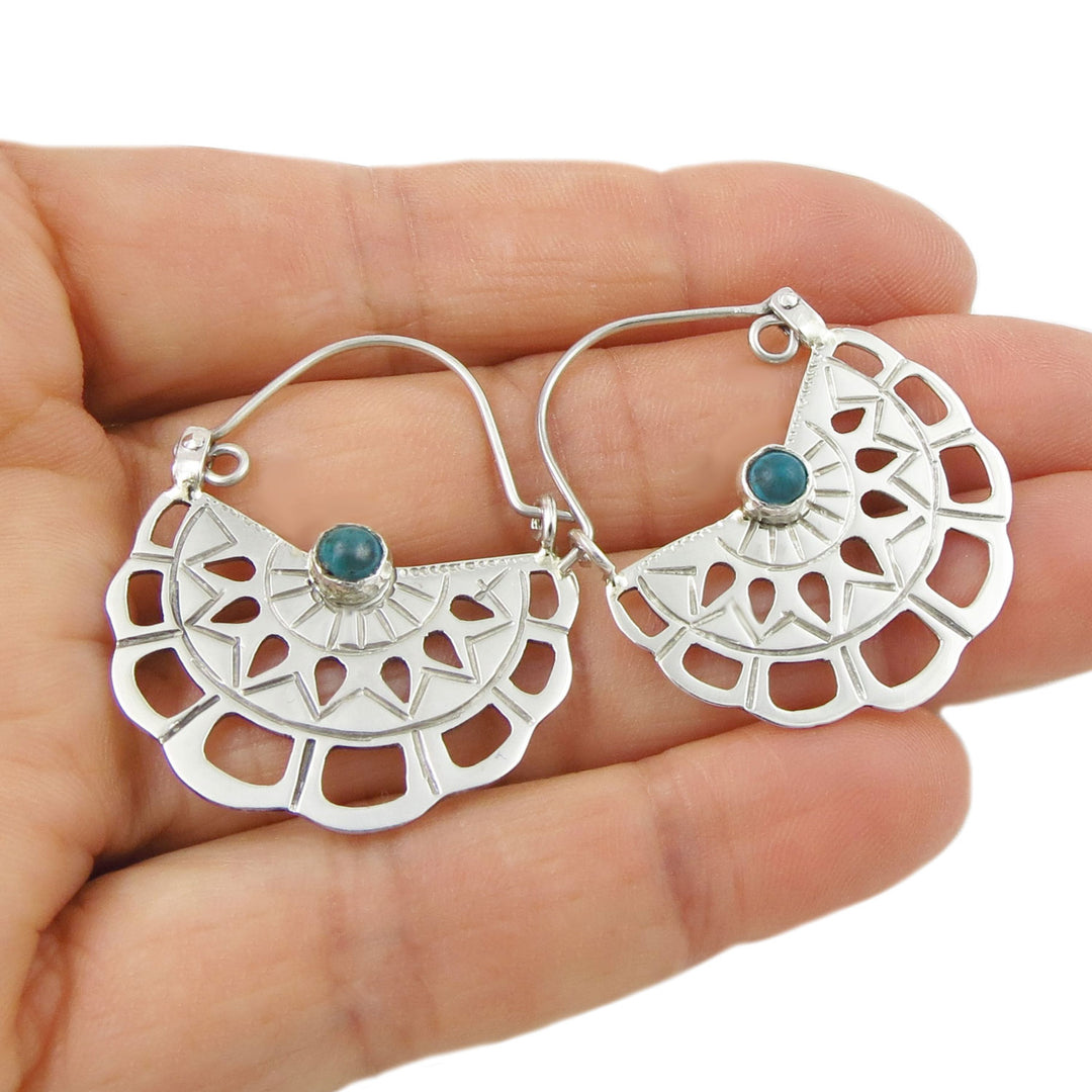 Mexican 925 sterling silver creole hoop earrings with turquoise gemstones held in a hand on a white background