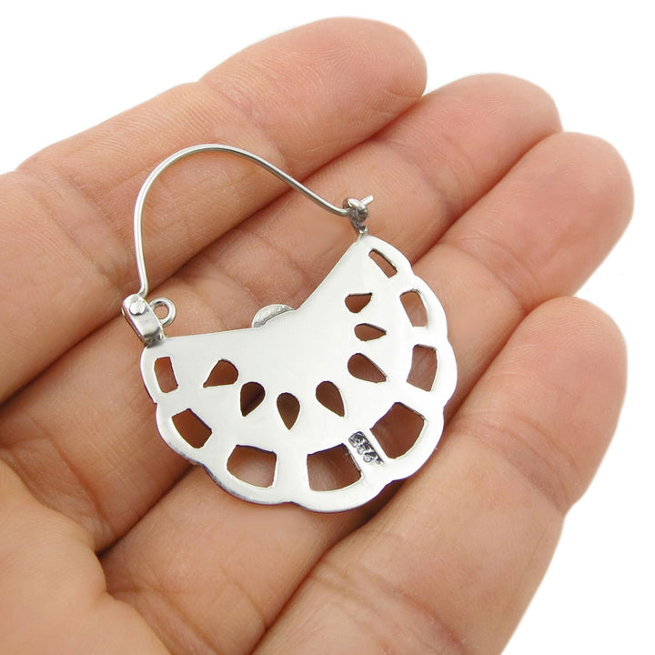925 Taxco sterling silver creole hoop earring held upide down in a hand against a white background