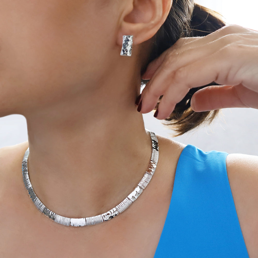 A close-up image of a sterling silver fitted collar necklace worn by a woman, with a focus on the necklace's fit around the neck.