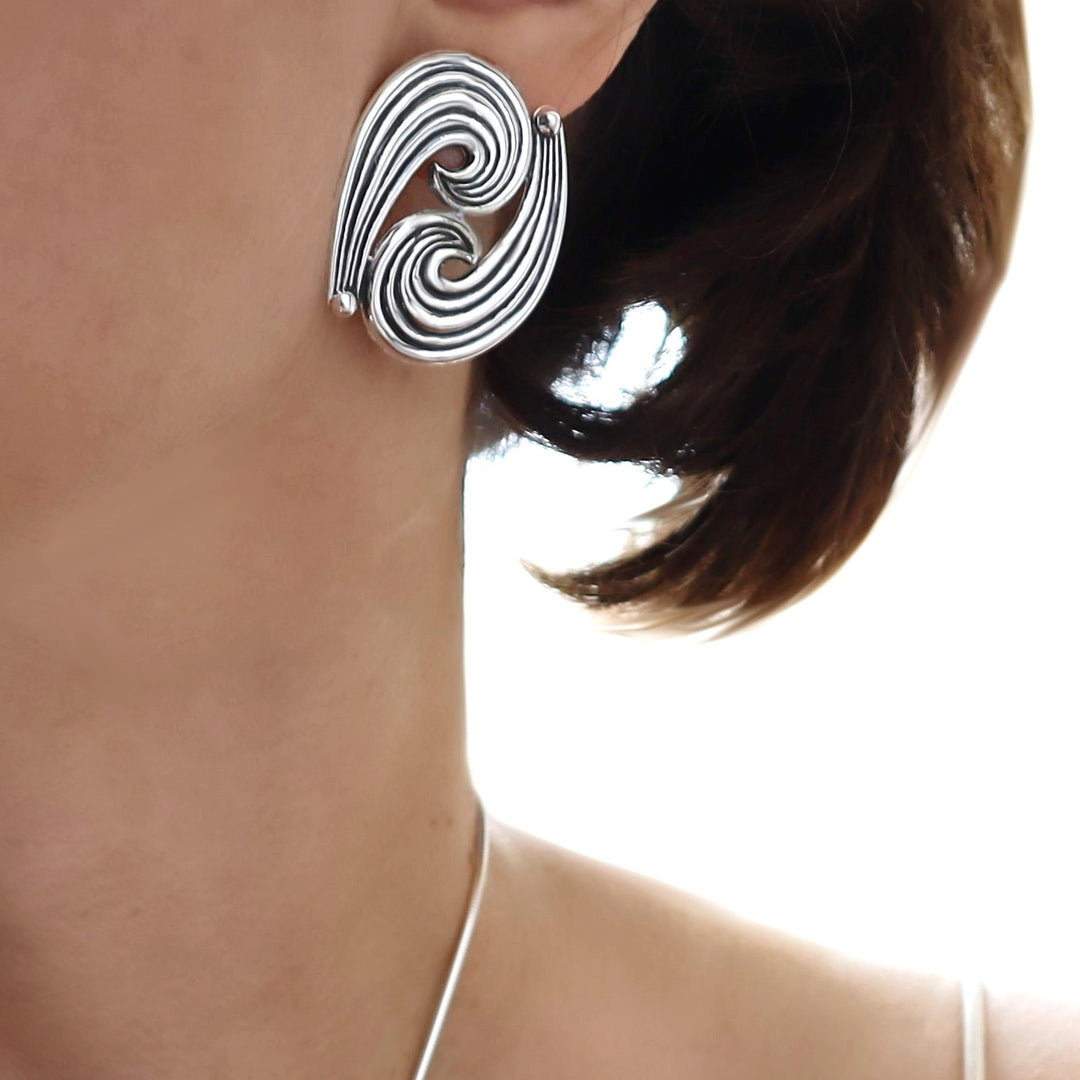 Sterling silver spiral earring worn by a person with a neutral background