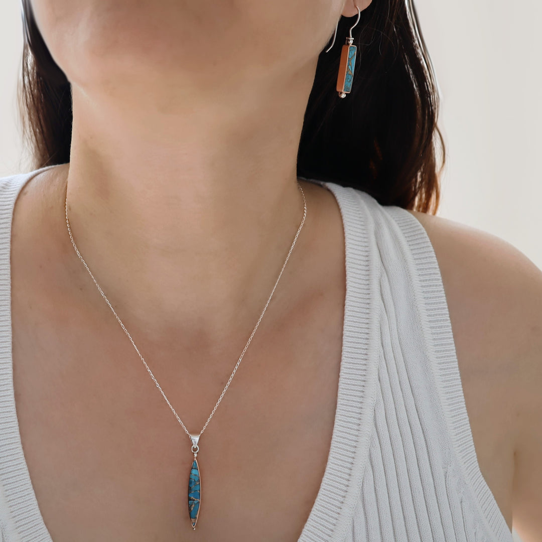 A woman in a white top wearing a blue amazonite drop earring and matching pendant necklace