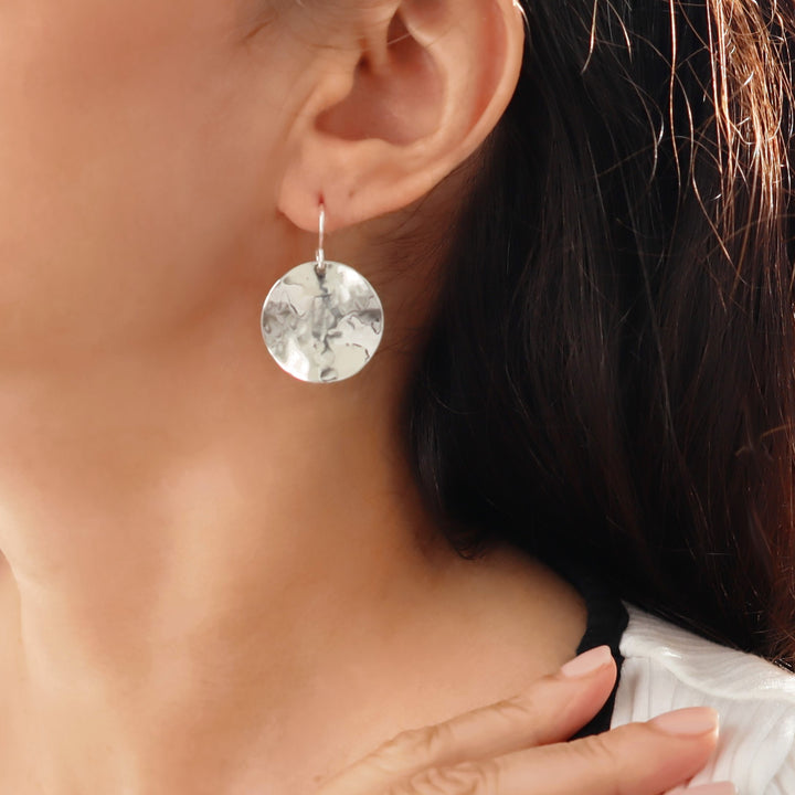 Close-up of a woman wearing a UK 925 sterling silver round earring with a textured hammered finish.