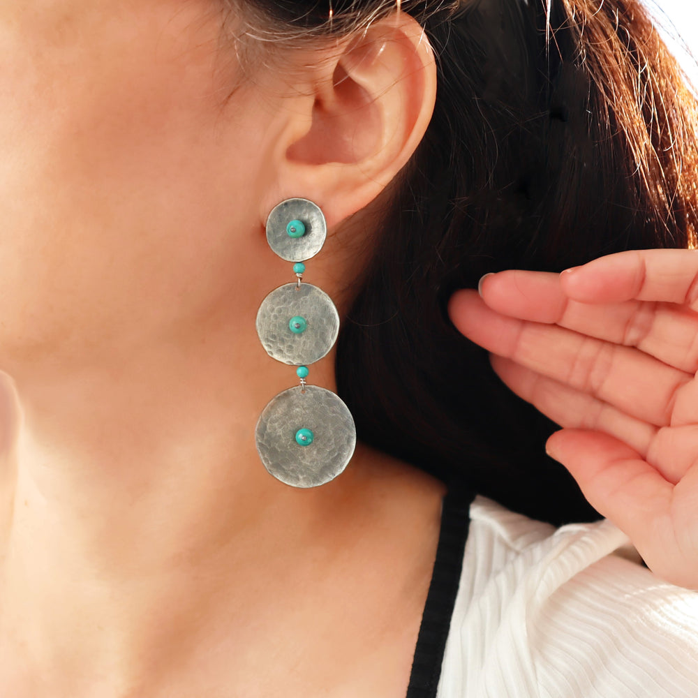 Maria Belen Nilson long 925 sterling silver chandelier drop earrings with turquoise bead accents worn by a woman with dark hair