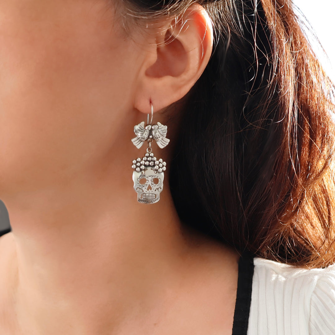 Close-up of a woman wearing a unique 925 sterling silver earring with a day of the dead sugar skull design.