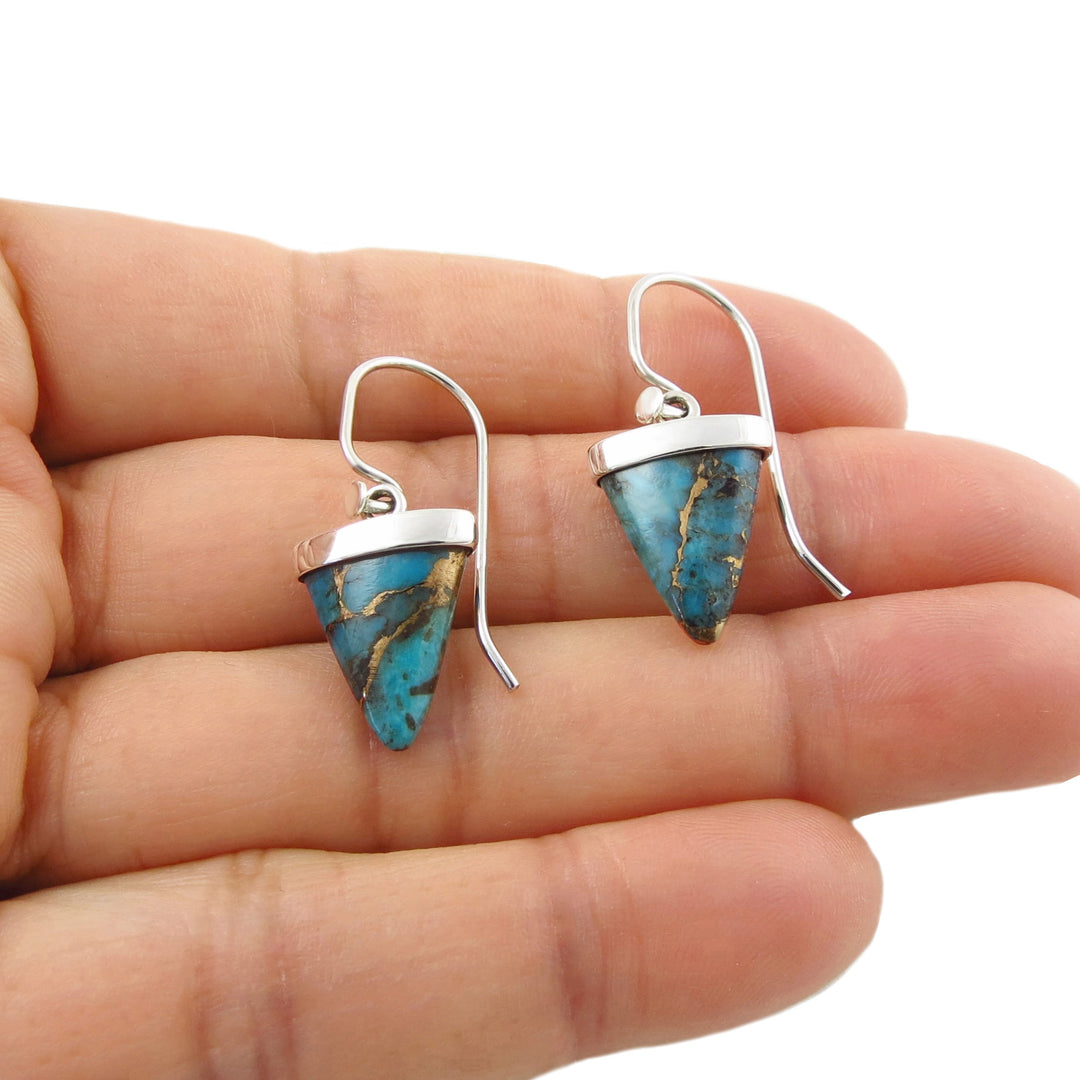 Mexican 925 silver and blue Mojave turquoise gemstone earrings with golden bronze veining held in a female hand. 