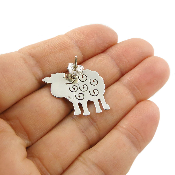 925 Silver sheep earring held upside down to show the post fasstener and the 925 hallmark and  held in a hand against a white background