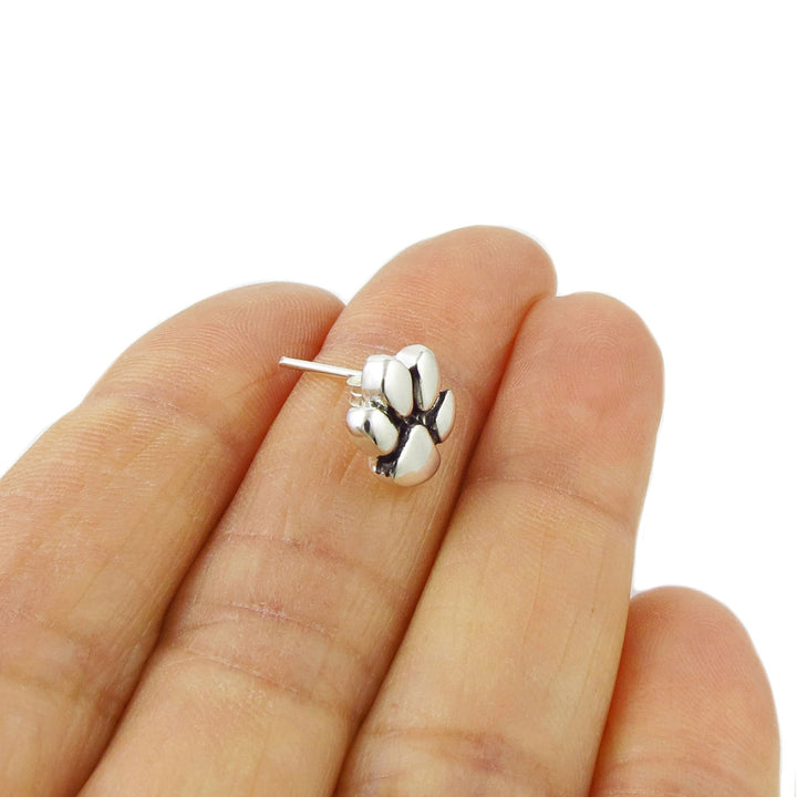 925 Sterling Silver animal paw print stud earring on a hand against a white background