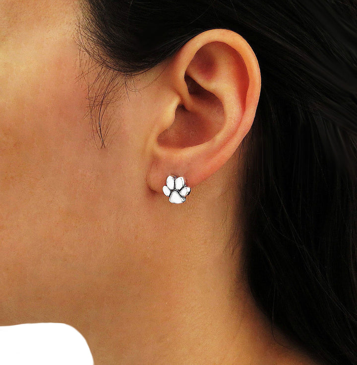 A sterling 925 silver dog or cat animal paw print stud earring worn by a woman with dark hair
