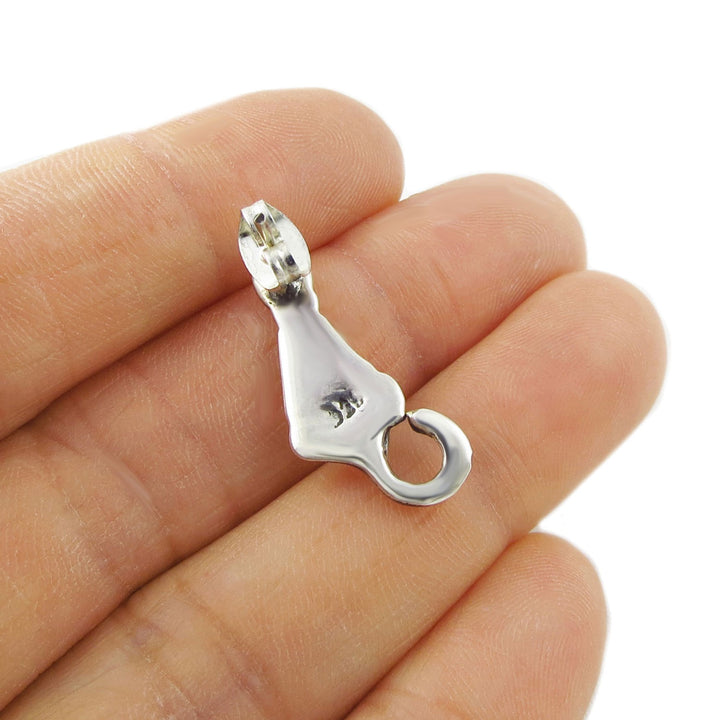 925 silver cat shaped earring held upside down to show the 925 hallmark in a woman's hand against a white background
