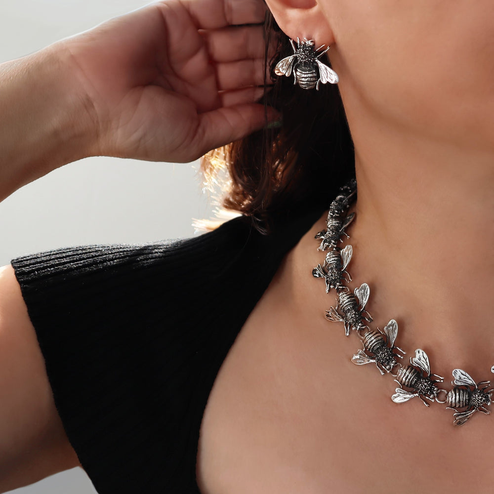 A woman in a black top wearing a unique handmade sterling silver bee necklace and matching earrings UK jewellery 