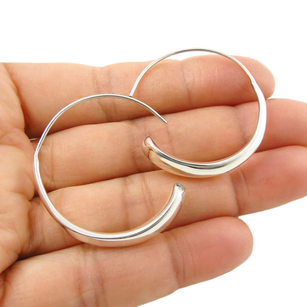 Large 925 sterling silver threader hoop earrings held in a hand against a white background