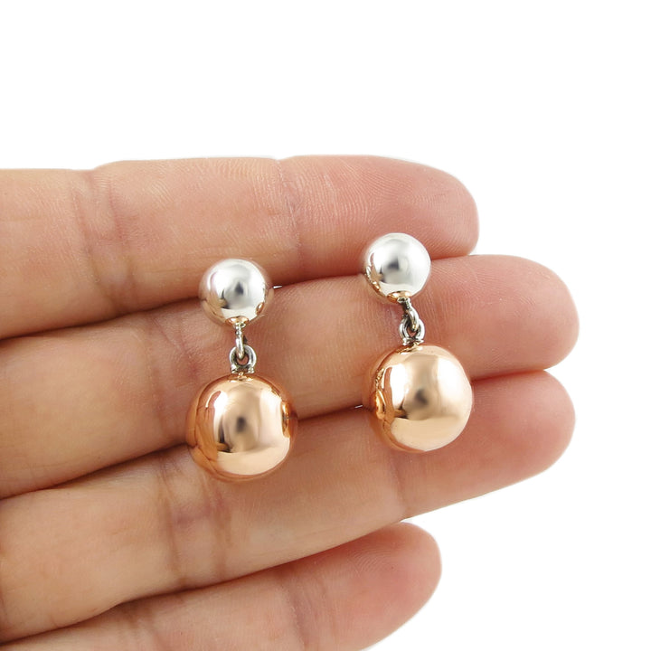 Mixed metal 925 silver and copper beaded ball earrings held in a person's hand on a white background