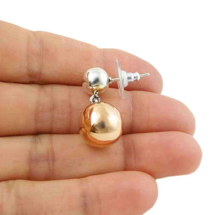 Copper and sterling 925 silver polished ball beaded earring on a hand with a white background