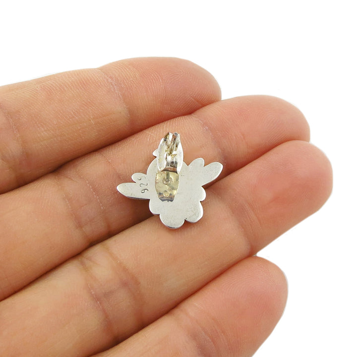Reverse of an angel-shaped 925 silver stud earring held in a woman's hand on a white background. 