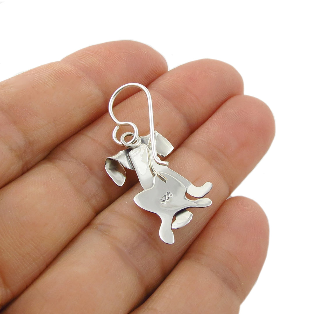 Reverse of a labrador dog shaped earring held in the palm of a hand for scale against a white background.