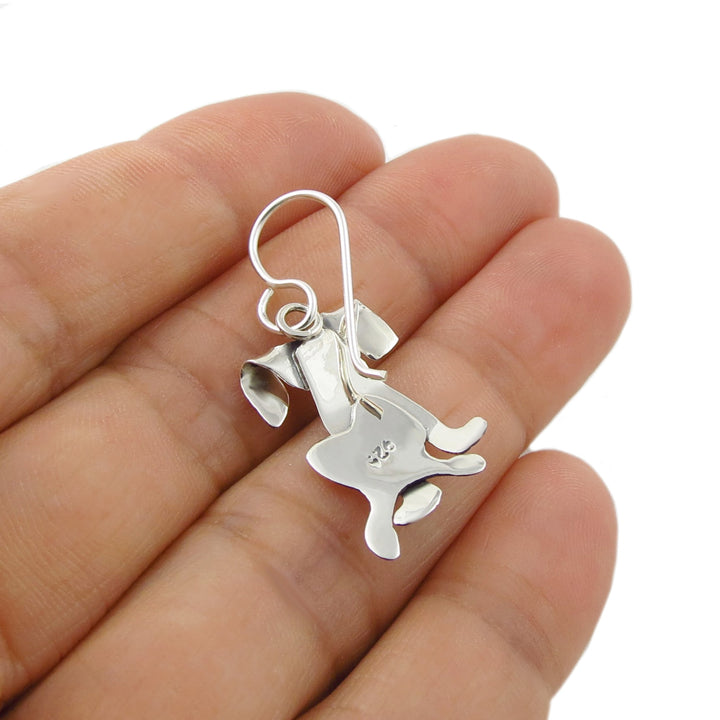 Reverse of a labrador dog shaped earring held in the palm of a hand for scale against a white background.