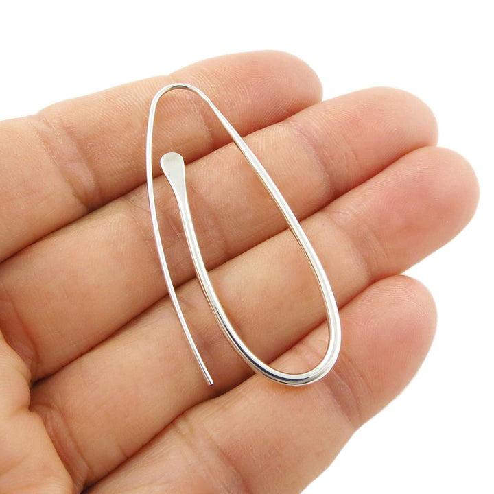 A long spiral threader earring in 925 Silver held between a woman's fingers on a white background