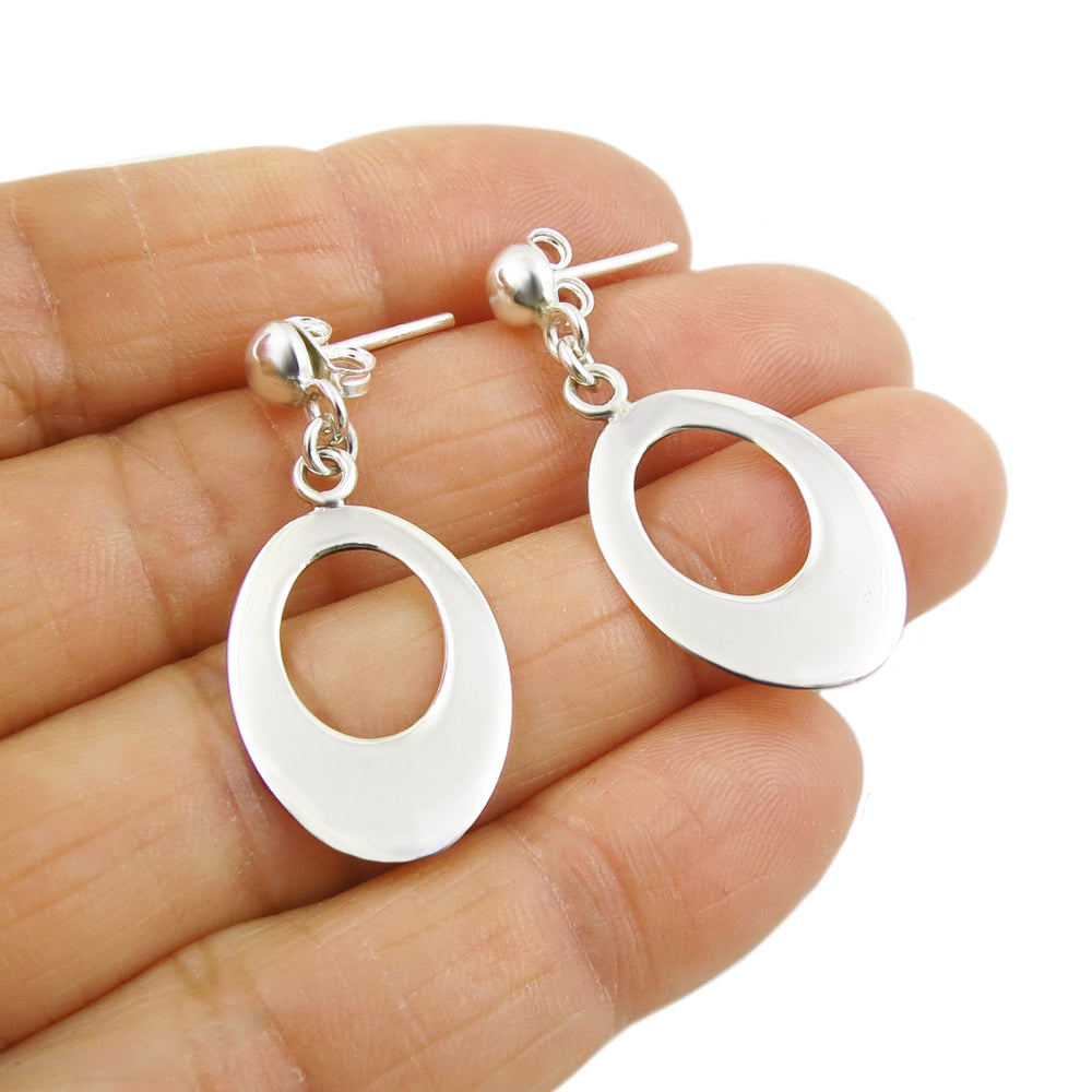 925 silver dangling oval drop earrings held in a person's hand