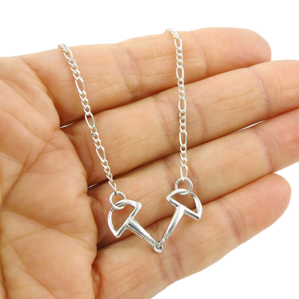Unusual horse snafflebit pendant and figaro chain nekclace for women held in a person's hand. 