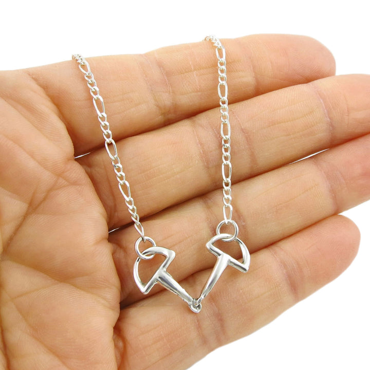 Unusual horse snafflebit pendant and figaro chain nekclace for women held in a person's hand. 
