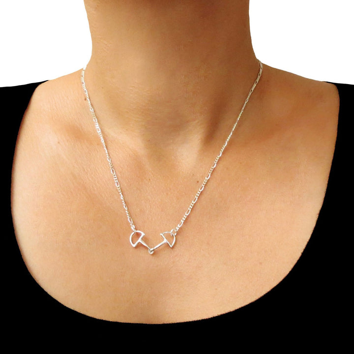 A unique figaro chain and horsebit snaffle pendant and chain necklace worn by a woman with a black top