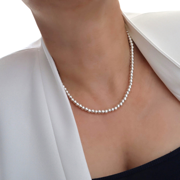 Beaded silver necklace worn by a person on a white background