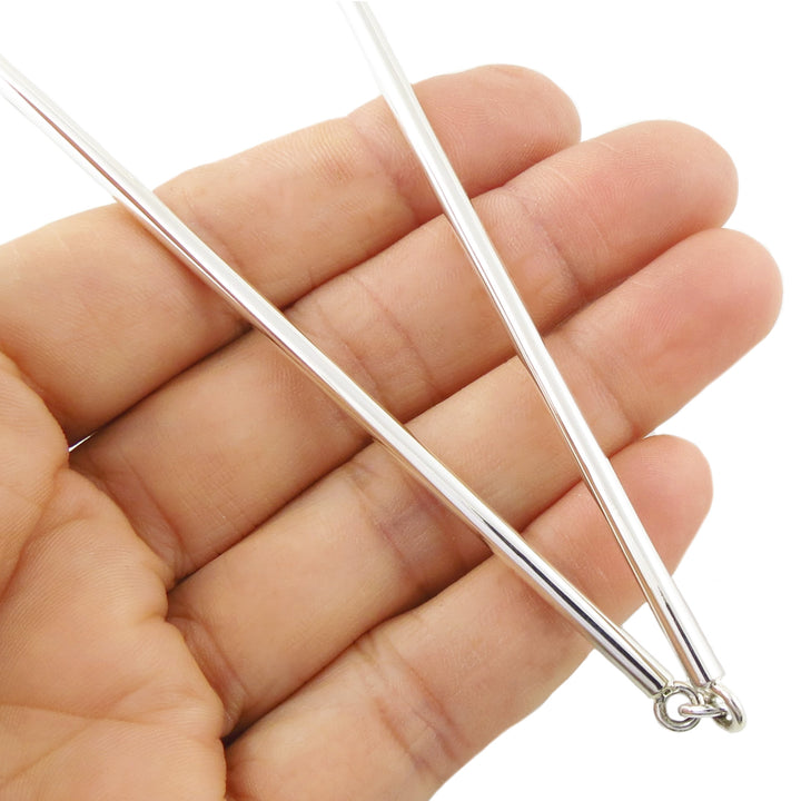 A close-up of a hand holding a very thin silver metal rod or chain necklace in sterling 925 silver with a small ring clasp, against a plain white background.