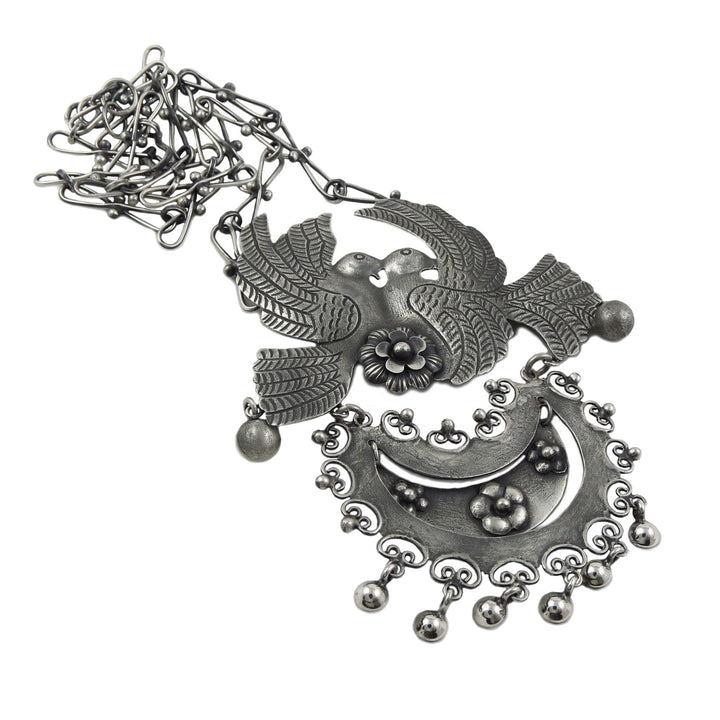 A large statement Mexican 925 sterling silver pendant necklace featuring stylised love birds with spread wings, a crescent moon, floral details, and dangling beads, shown on a plain white background.
