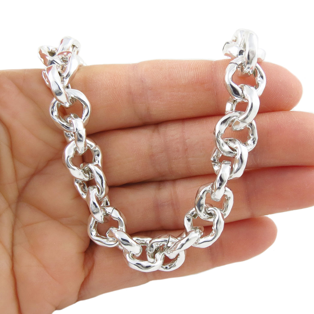Silver chain necklace held in a hand on a white background