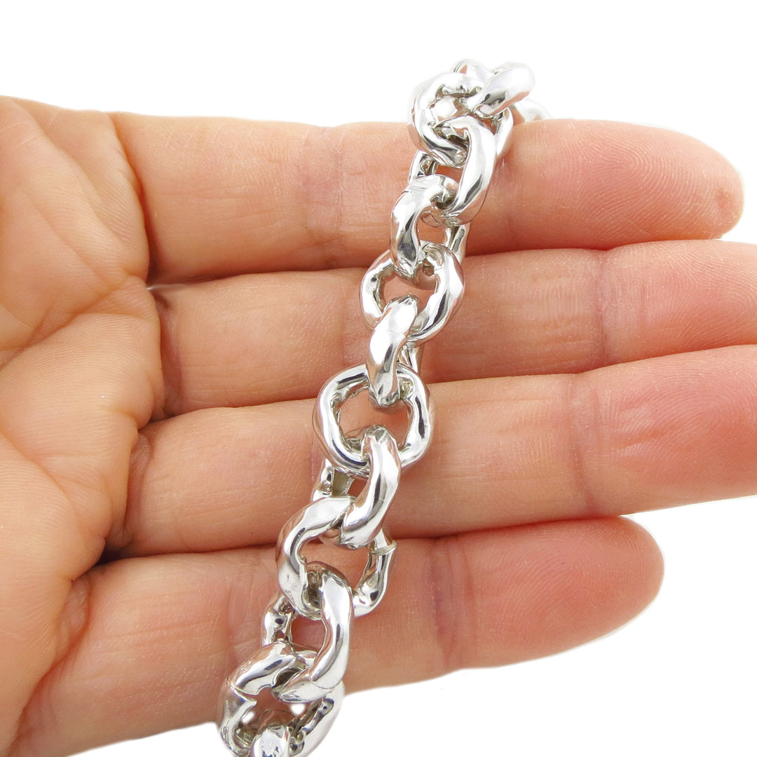 Hammered silver chain necklace held in a hand on a white background