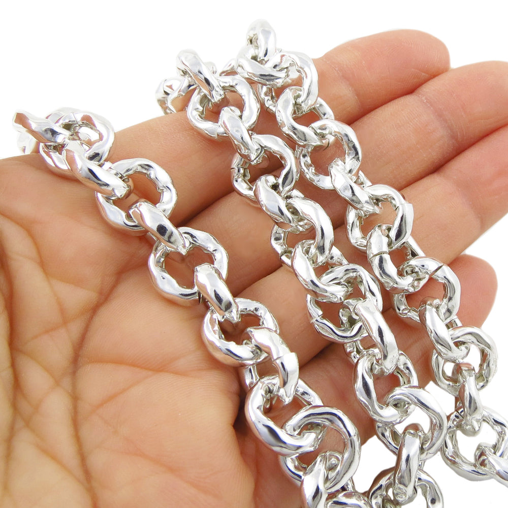 A person's hand holding a sterling silver chunky curb chain necklace with a hammer-textured finish.