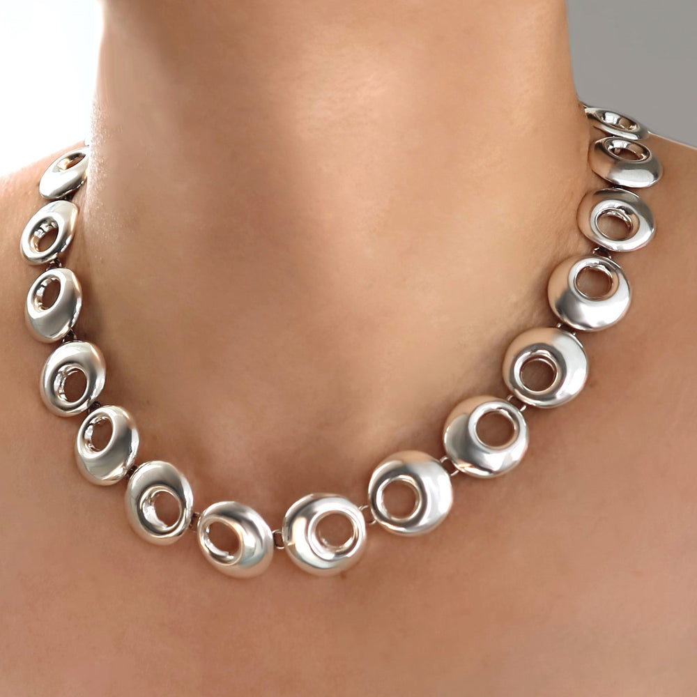 Silver necklace with circular design on a person's neck