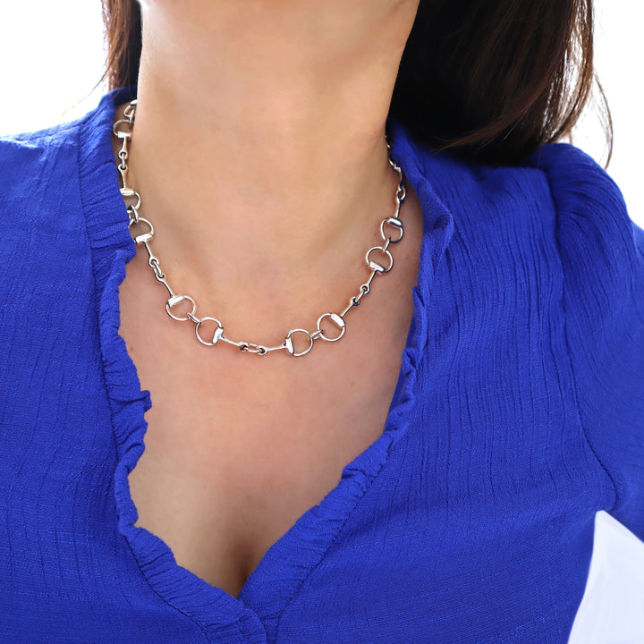 Silver snafflebit chain necklace worn by a woman in a blue top