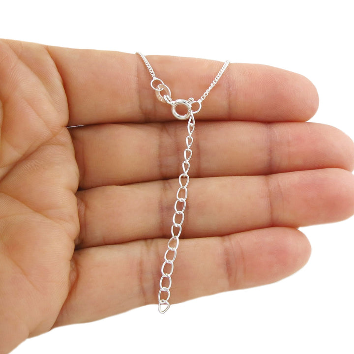 Sterling 925 Silver curb chain with an extension for making the length larger held in a hand on a white background