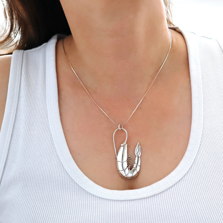 Silver lobster pendant necklace on a person wearing a white top