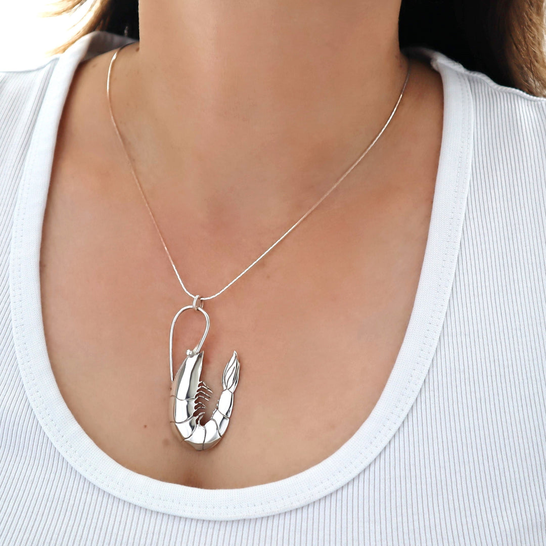 Silver lobster pendant necklace on a person wearing a white top