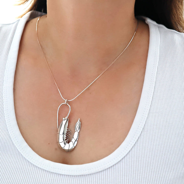 Silver lobster pendant necklace on a person wearing a white top