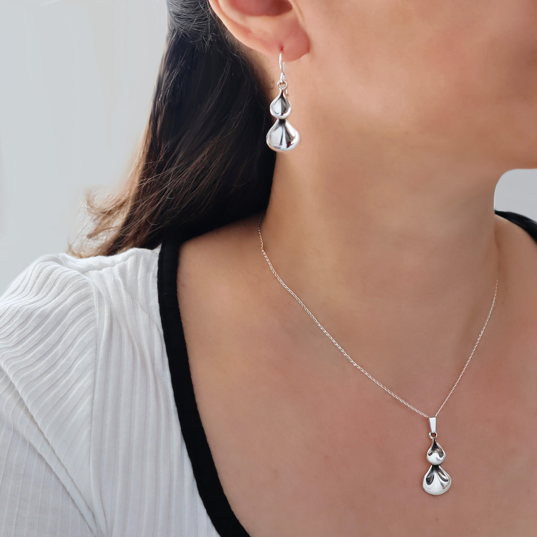 Silver petal earrings worn by a person with a white top.
