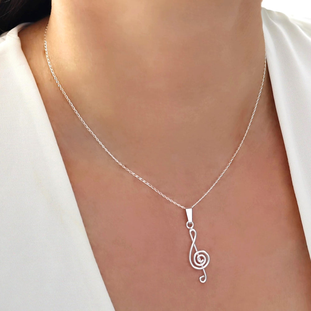 925 sterling silver necklace with a treble clef music note pendant on a person wearing a white shirt.