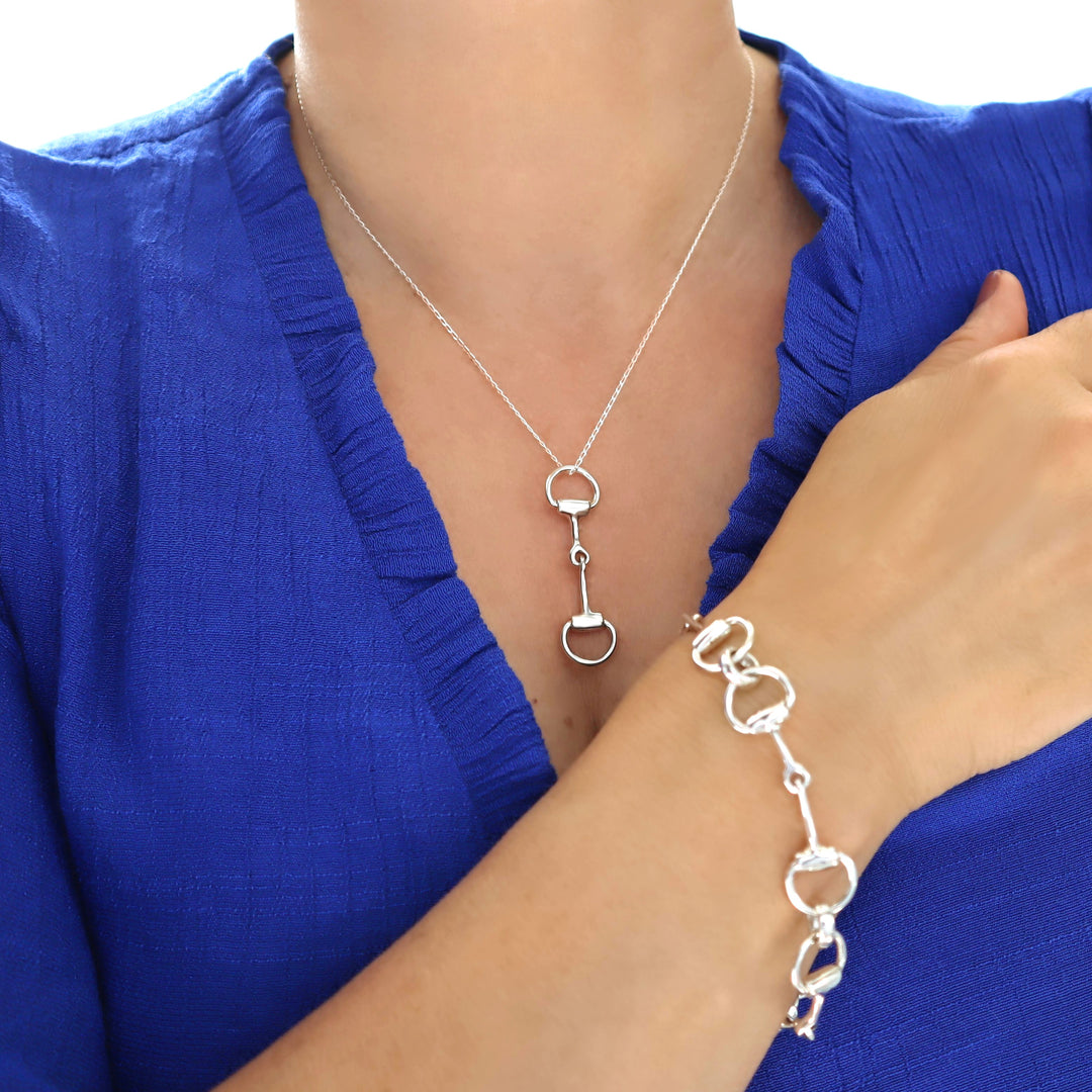 A woman wearing a snafflebit pendant and matching snaffle bracelet in sterling silver. 