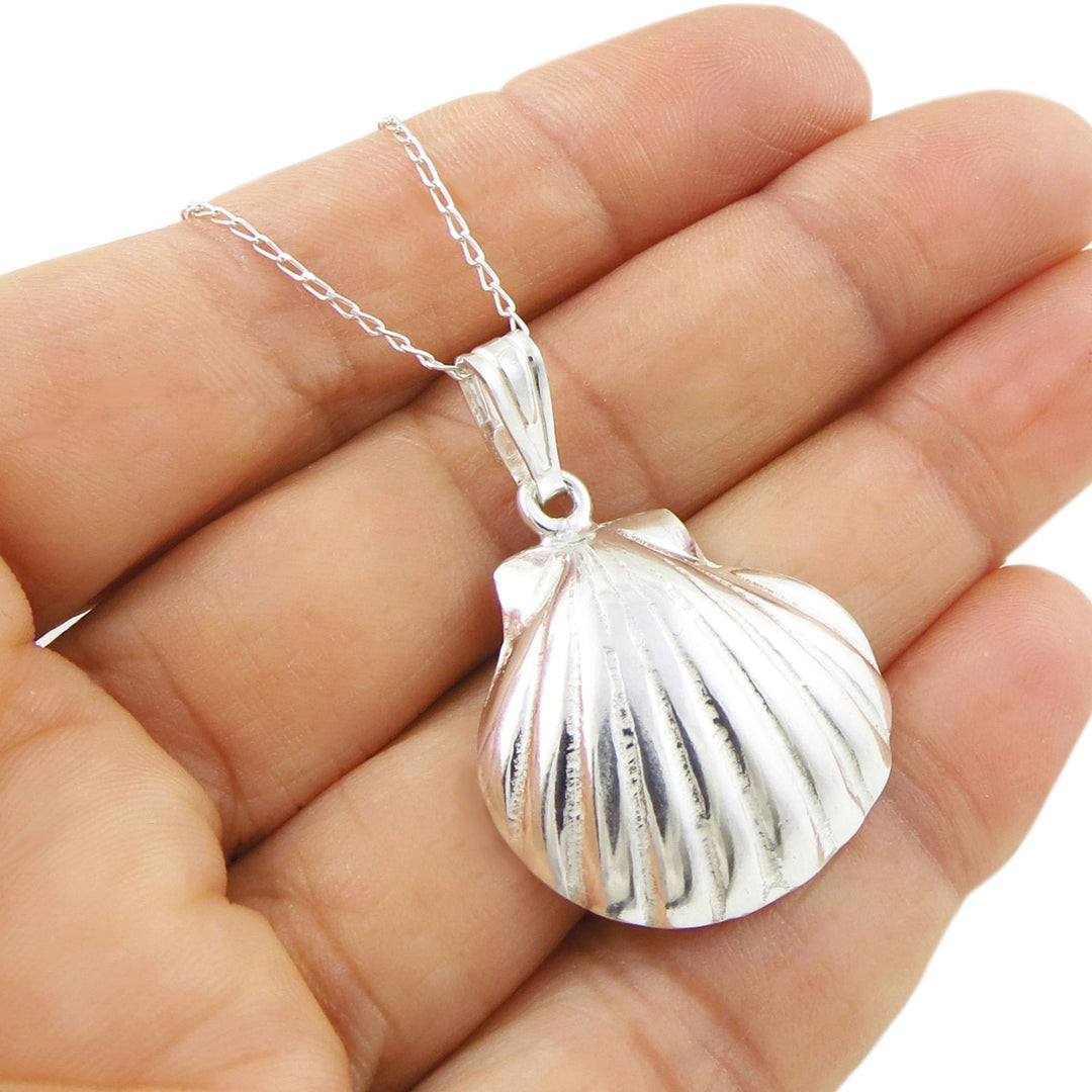 Sterling 925 silver seashell pendant jewellery on a chain held in a hand against a white background