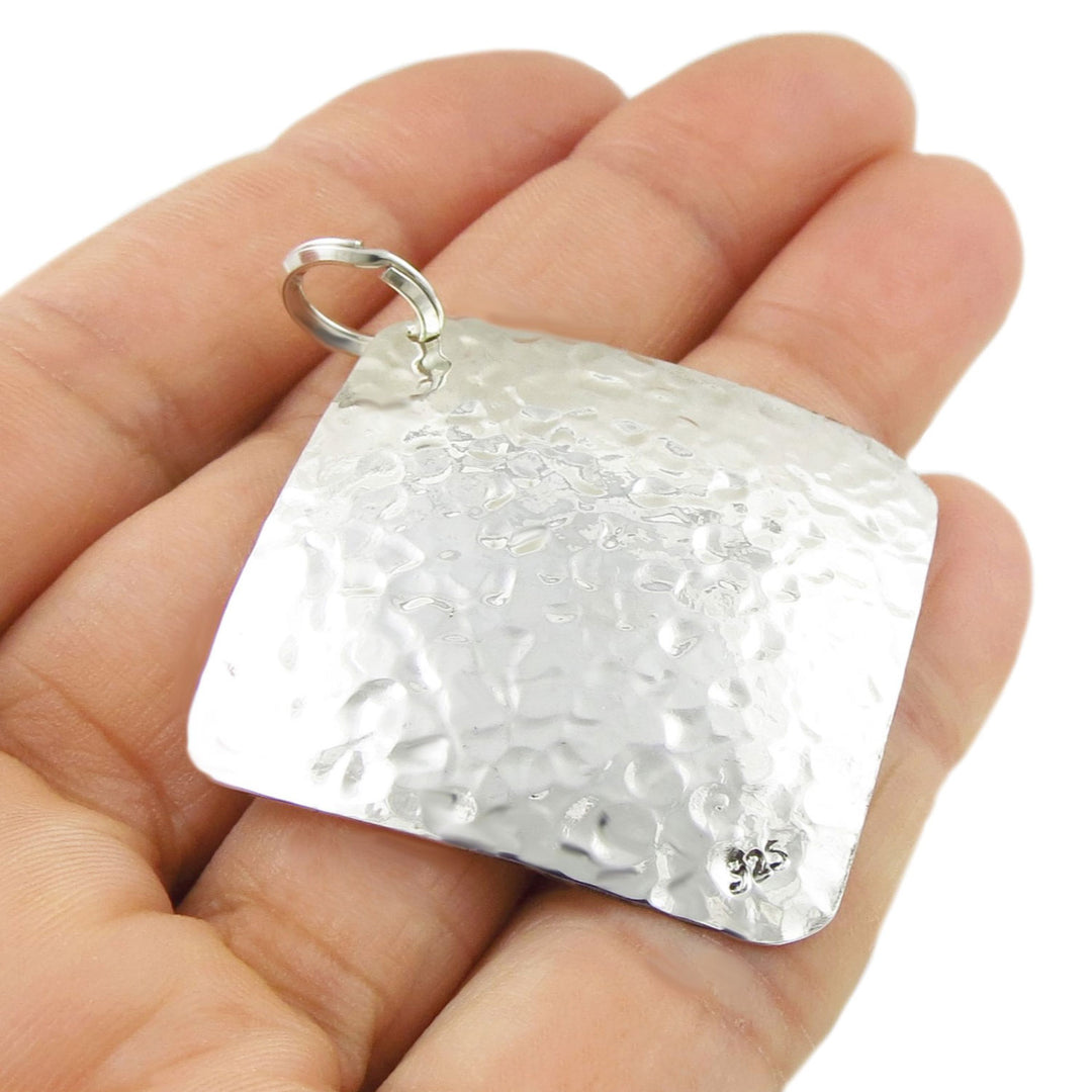 925 sterling silver pendant necklace held upside down in a hand to show the 925 hallmark against a white background
