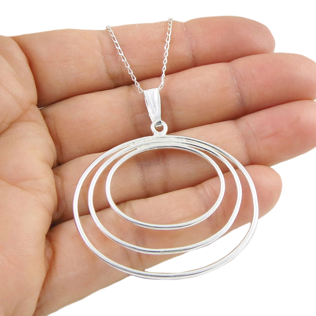 Wide oval sterling 925 silver pendant necklace held in a hand against a white background