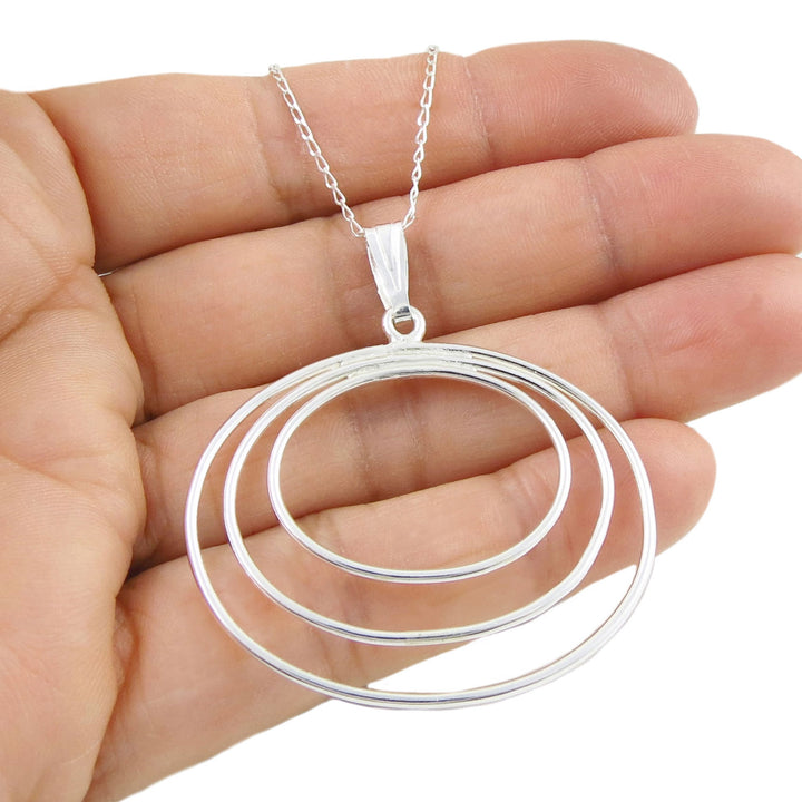 Wide oval sterling 925 silver pendant necklace held in a hand against a white background