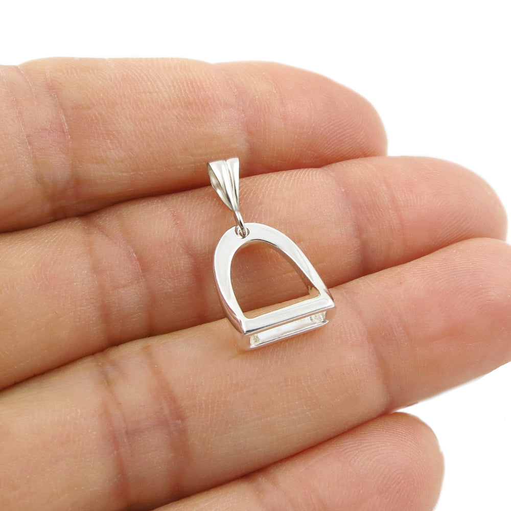 Sterling 925 silver horse stirrup pendant jewellery held in a person's hand on a plain background. 