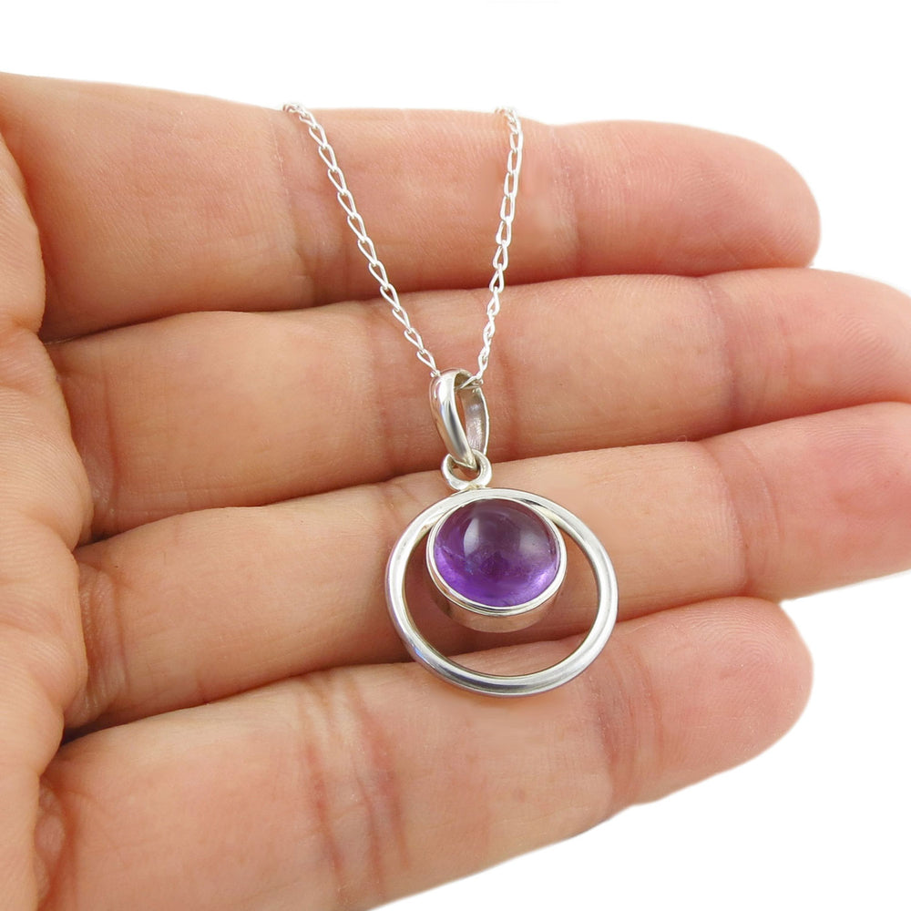 Sterling 925 silver pendant and chain necklace with a purple amethyt gemstone held in a hand on a white background